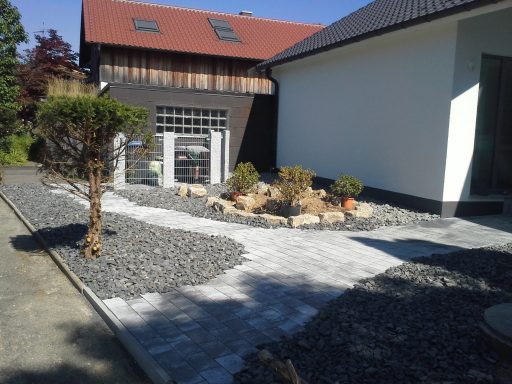 Eingang zu einem modernen Haus mit kiesbedecktem Weg und Pflanzen.