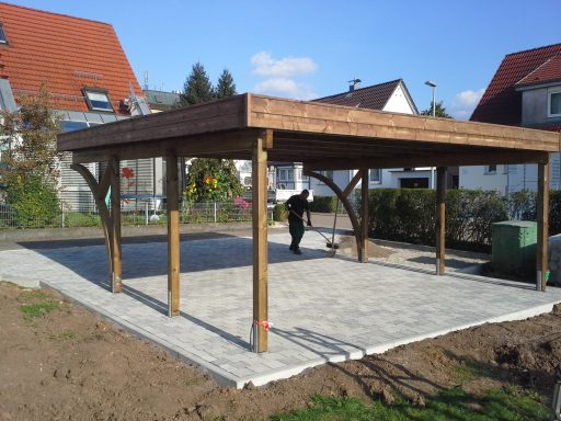 Pavillon mit Holzdach und gepflastertem Boden in einem Garten.